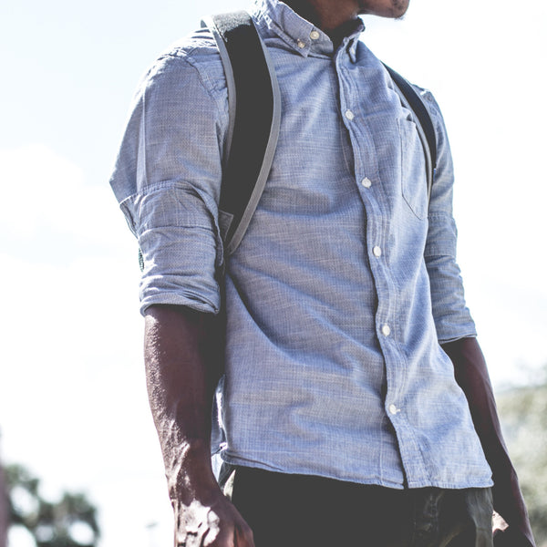 man wearing a blue button up with a black backpack