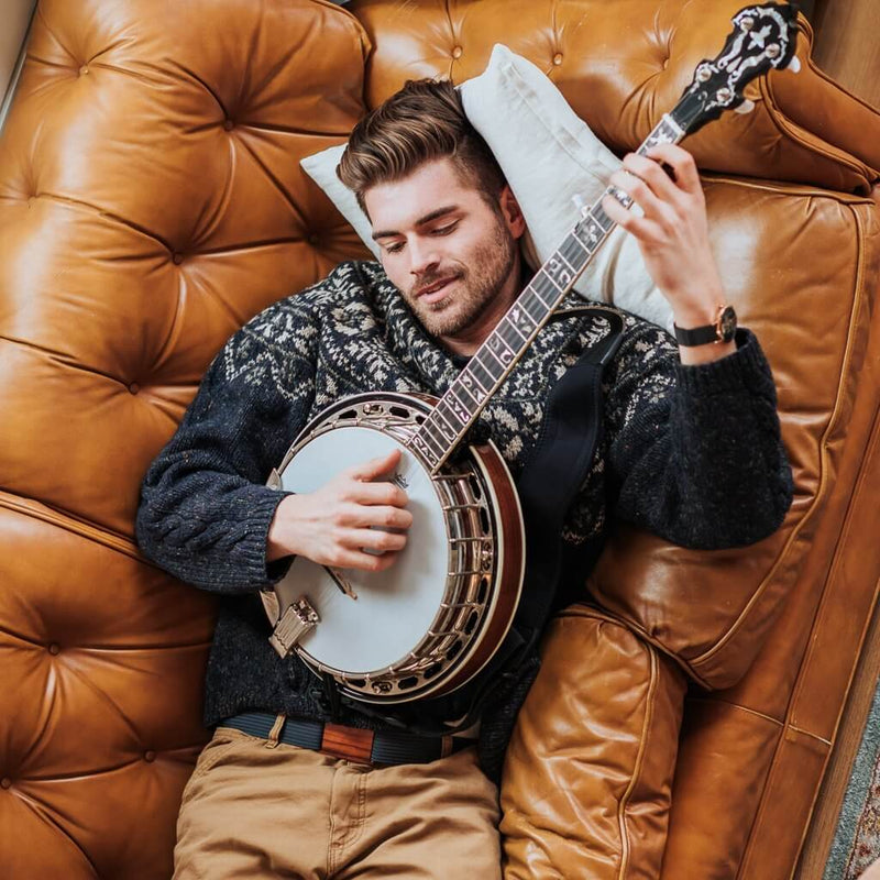 a man laying on the couch with a banjo and a grip6 belt