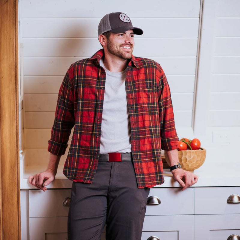 man leans on a dresser in flanel