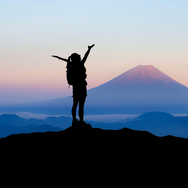 woman standing atop a mountain peak