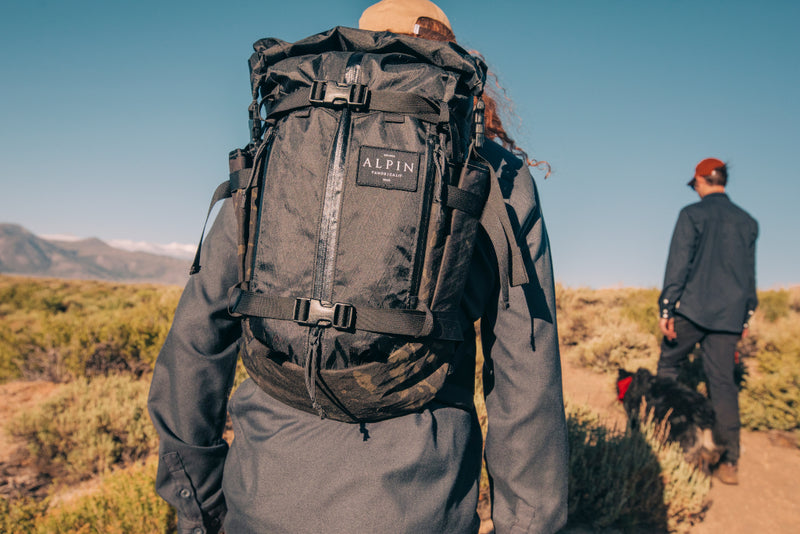 closeup of a backcountry backpack as two friends hike in the mountains