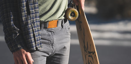 A man with a wooden belt buckle to match his longboard.