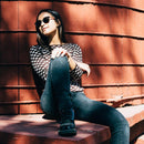A woman wears Ada Eco Yellow Tortoiseshell/Brown Polarized Lens shades as she leans against a silo.