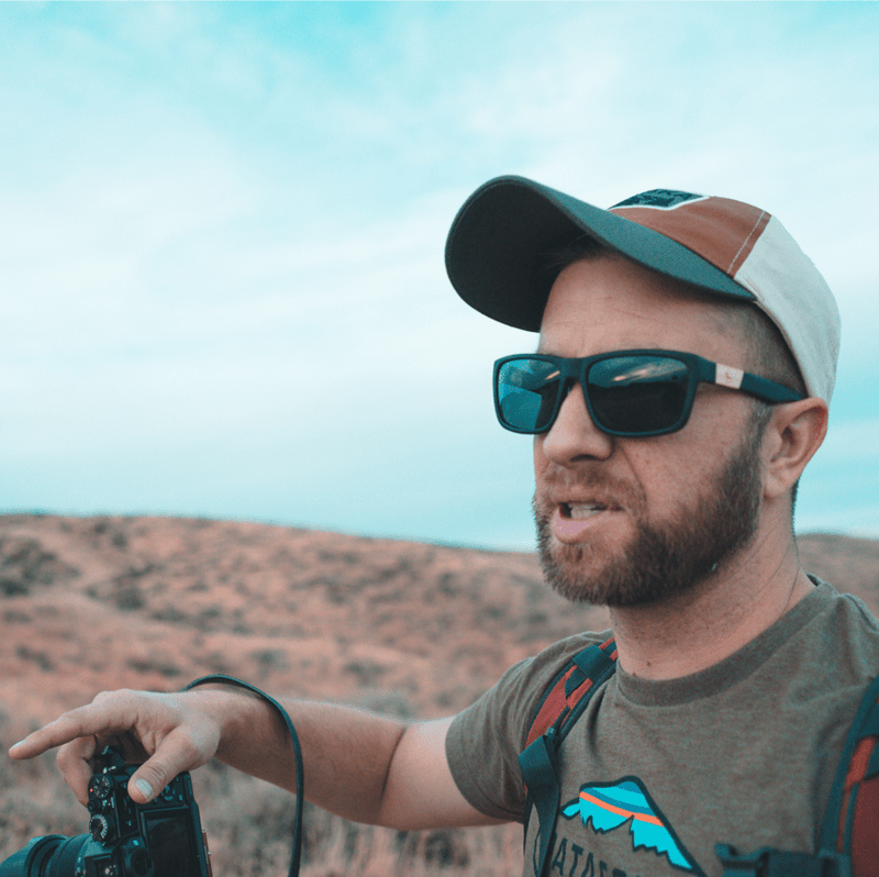 A man wears sunglasses in the desert.