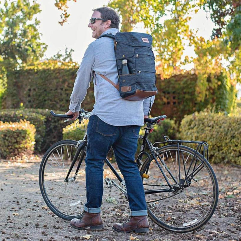 A man wears the Denim Presidio Pack while walking his bike.