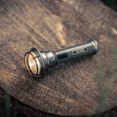 barebones vintage flashlight laying on tree stump