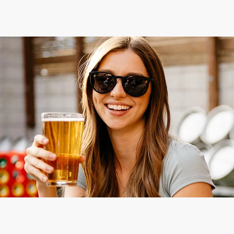 Matte Black Knockaround Mary Janes on a smiling woman holding a beer