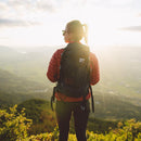 A woman stands on a cliff wearing the Beast28 Technical Backpack