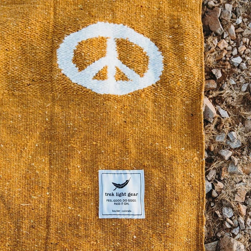 corner of golden peace blanket displaying trek light gear badge