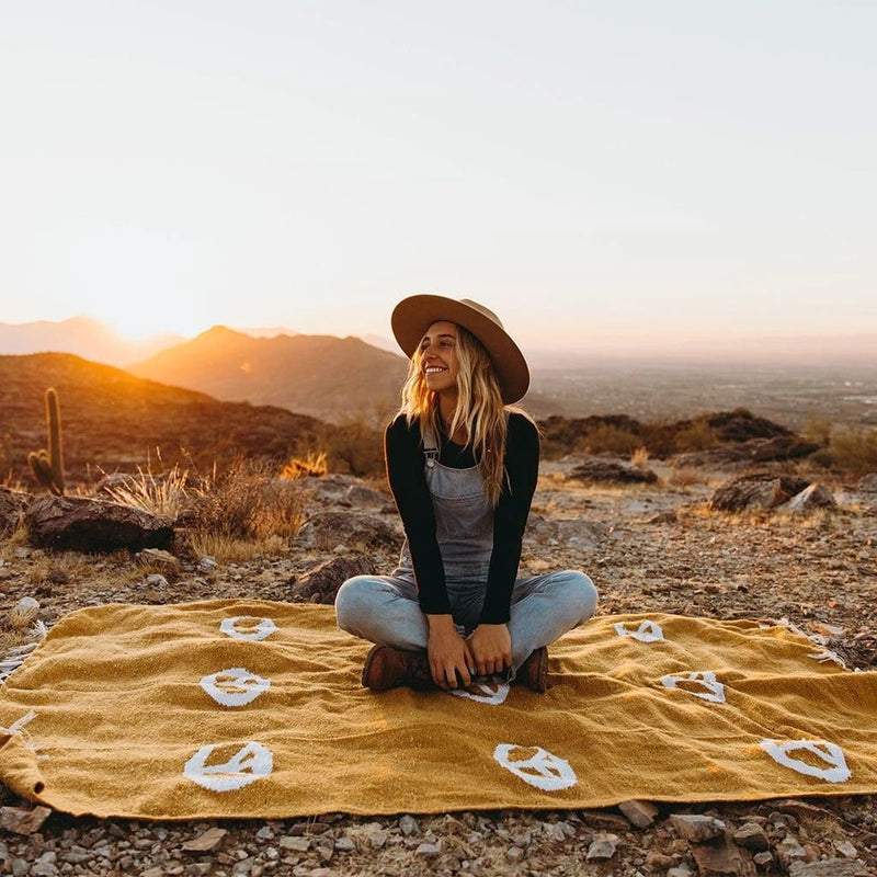 woman sitting cross legged on a blanket in the desert