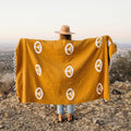 woman holding up golden peace sign blanket against her back
