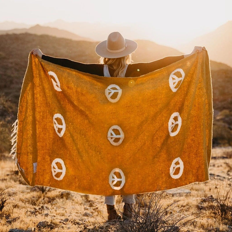 woman facing the morning sun holding up blanket against her back