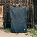 Trek Light Gear Greyson Blanket--against a burned cabin