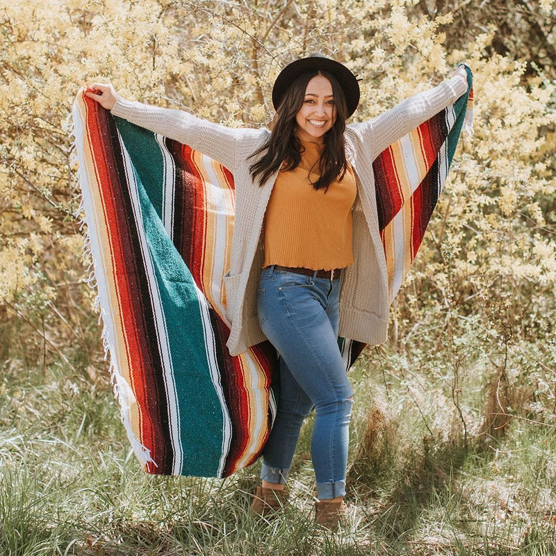 woman smiling while holding monterey blanket in outstretched arms